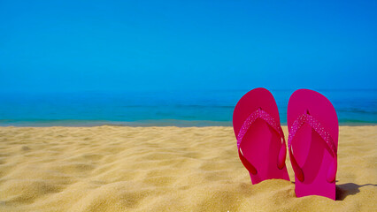 Pink sandals in sand on sunny beachfront overlooking clear blue ocean