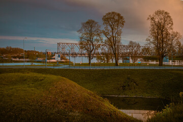 Obraz premium Urban skyline with street, bridge and city park in spring golden hour evening