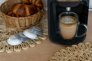 Capsule coffee maker with glass latte cup and capsules for home coffee making. Black small coffee maker for daily drink for apartment and office.