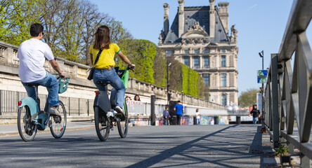 Une jeune fille et un jeune homme à Paris en vélo.