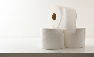 Three soft stacked toilet paper rolls on table isolated background