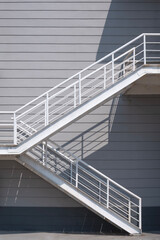 Fire escape on industrial office building wall with light and shadow on surface, front view and vertical frame