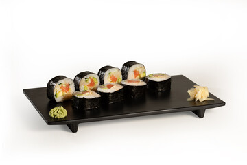 Tasty futomaki served in a black plate with wasabi and ginger on white background, stock