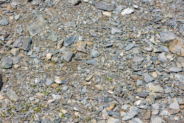 Pile of various gray and brown natural rocks and stones under bright sunlight - full-frame...