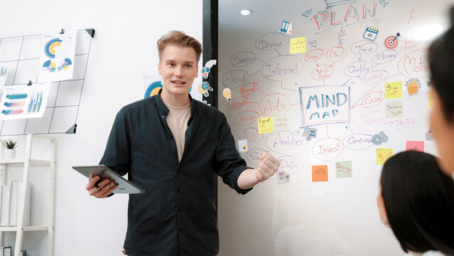 Fototapeta Professional male leader presents start up project by using mind map, colorful sticky notes and business statistic graph with confident while investor listening carefully. Immaculate.