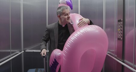 Happy priest leaving for summer vacations, he is carrying luggage and a huge inflatable toy in the elevator