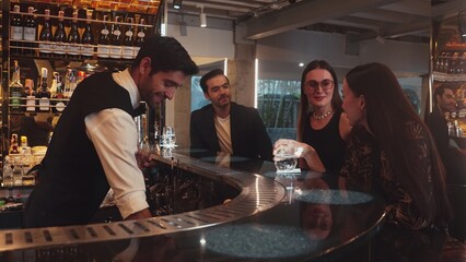 Smart bartender with VIP customer at luxurious bar greeting new beautiful guest at counter in...