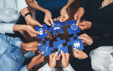 Diverse corporate officer workers collaborate in office, connecting puzzle pieces to represent...
