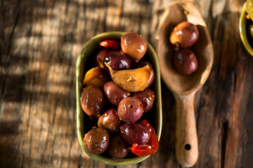 Olives, homemade marinated colorful olives with herbs and spices on rustic table, close up. Healthy Mediterranean vegan food. Top view, flat lay 