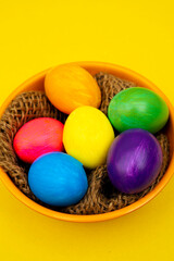 Colorful Easter Eggs in Orange Bowl on Yellow Background