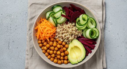 Bowl with healthy food including chickpeas carrots avocado cucumber and beets.