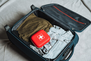 A large suitcase that is packed with an assortment of clothes along with a wellstocked first aid...