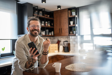 Happy freelancer celebrating success on smartphone in modern kitchen