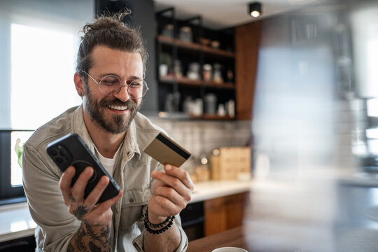 Happy man making online payment using credit card and smartphone