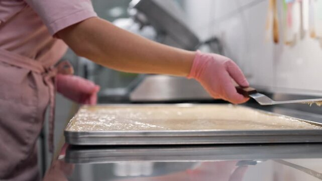 Pastry chef smooths surface of batter on baking parchment. Cooking sponge cake