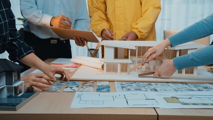 A diverse team of professionals engages in an architectural design meeting, reviewing blueprints...