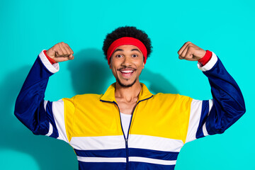 Energetic young man in retro sportswear showcasing vibrant confidence on a turquoise background, embodying a sporty and joyful lifestyle