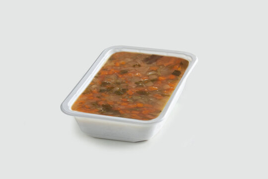 open plastic pack containing vegetable and legume soup. Pack-shot of white plastic box on white background