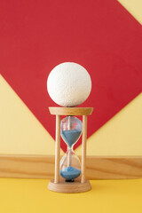 Hourglass with a flowing blue sand inside and plastic foam ball on the top