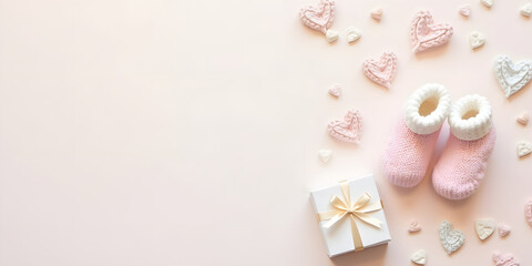 baby decorations featuring pair of knitted baby booties, heart shapes, and a gift box with ribbon on a pastel background