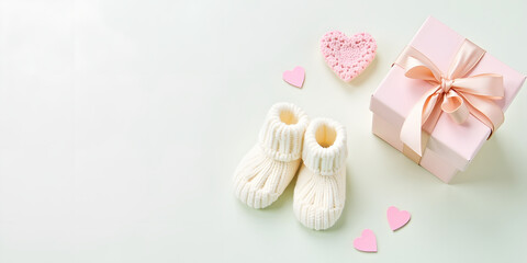 baby decorations featuring pair of knitted baby booties, heart shapes, and a gift box with ribbon on a pastel background