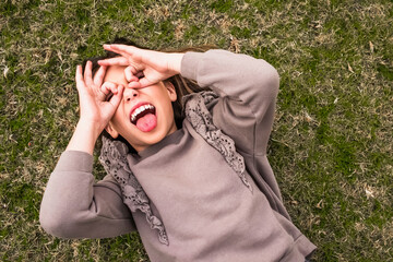 Playful child lying on grass making funny faces and gestures
