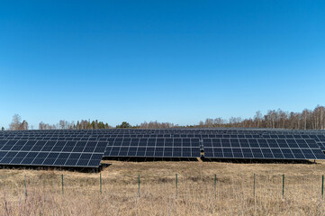 Solar panel installation in open land under clear blue sky during daylight