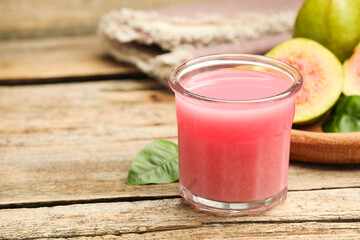 Refreshing guava juice and fresh fruits on wooden table, closeup. Space for text