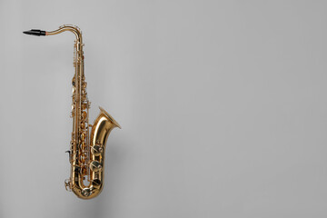 Golden saxophone on light grey background. Space for text
