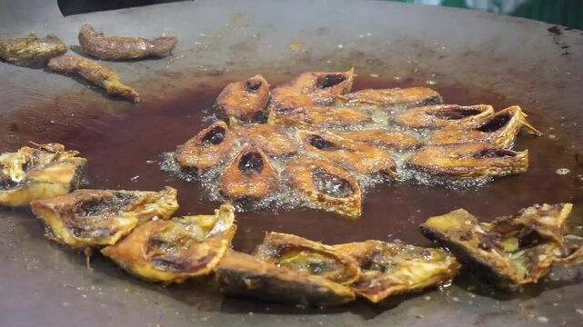Hilsha fish is fried in a big pan along with shrimp and eggplant, Hilsha Fish and shrimp Simmering in mustard oil, traditional Bengali style fried hilsa and eggplant	