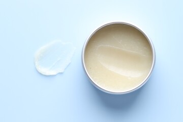 Moisturizing lip balm and jar on light blue background, top view