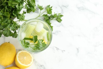 Healthy drink with parsley, cucumber, celery and lemons on white marble table, flat lay. Space for...
