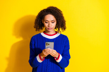 Young Woman Using Smartphone Against Yellow Background Wearing Cozy Knitwear in Casual and Stylish...