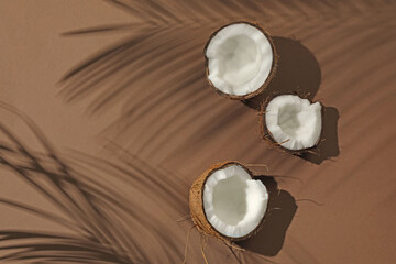 Fresh coconut and shadow cast by tropical palm on beige background, flat lay. Space for text