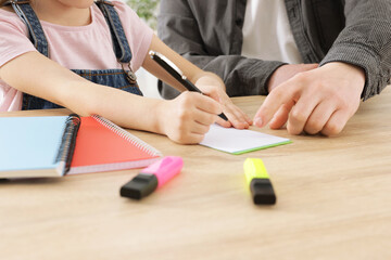 Teacher having lesson with little girl at desk indoors, closeup
