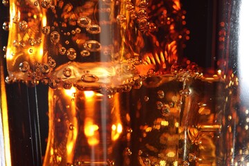 Refreshing cola with ice cubes as background, macro view
