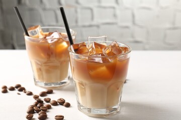 Tasty iced coffee and beans on white table, closeup