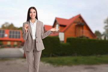Real estate agent holding key and welcoming to house outdoors