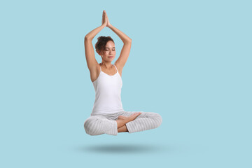 Obraz premium Young woman levitating during meditation on light blue background. Practicing yoga