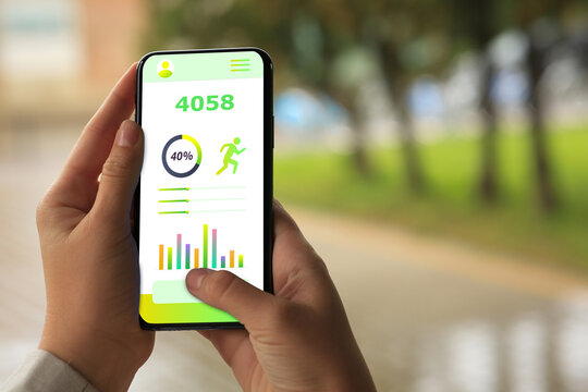Woman using step counting app on smartphone outdoors, closeup - Powered by Adobe