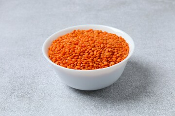 Red lentils in a bowl on a gray background