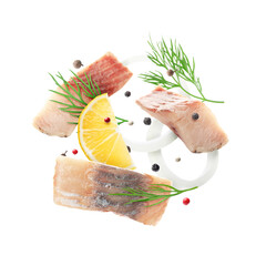 Pieces of herring, lemon, onion, dill and peppers mix in air on white background