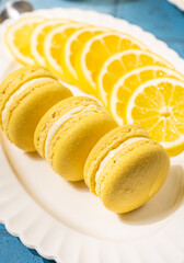 Lemon macarons resting on white plate with lemon slices