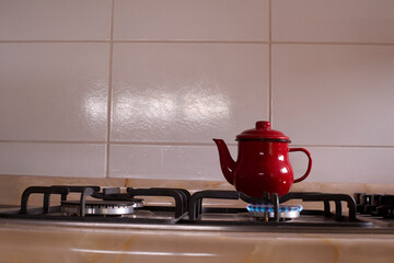Red vintage kettle boiling on gas stove burner, creating warm morning tea atmosphere in homey kitchen setting, promising cozy start to day