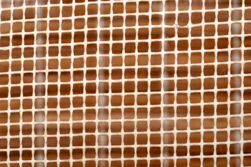 Macro close-up revealing white plastic mesh exhibiting geometric square pattern, contrasting against deep brown background, ideal for textural design elements