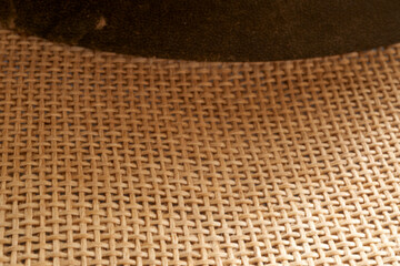 Woven straw hat macro revealing intricate fiber interplay, textured surface accentuated by contrasting leather band, showcasing natural weaving craftsmanship