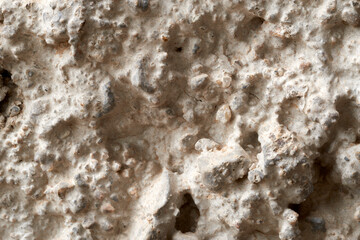 Close-up view of a rough concrete surface revealing small stones, cracks, and intricate textures, providing a detailed look at the material's composition