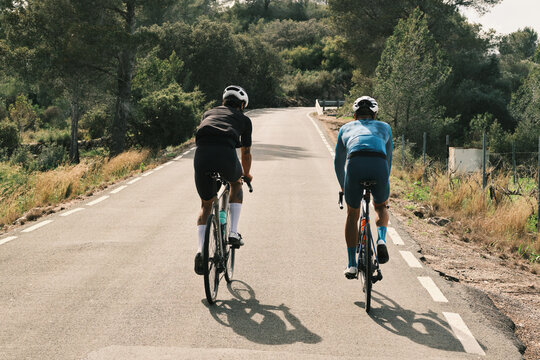 Two cyclists ride along a scenic country road, enjoying a sunny day.  Their journey showcases athleticism and the beauty of outdoor adventure.