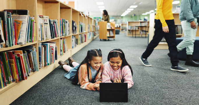 Education, library and girls on floor, tablet and online learning with smile, knowledge and relax. Kids, students or friends on ground, tech or storytelling with ebook, break or bonding together