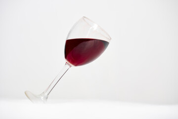 Tilted red wine glass on white background